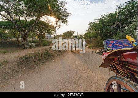 Oxcart e carrozza a cavallo turistica che viaggia su una strada polverosa a Bagan Myanmar. Birmania Foto Stock