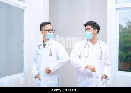 Ritratto di due medici che si salutano a vicenda urlando i gomiti Foto Stock
