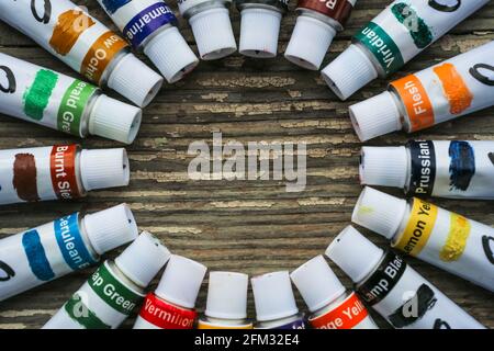 Tubi di vernice, pennelli per pittura e tavolozza coltelli sul vecchio sfondo di legno. Foto Stock