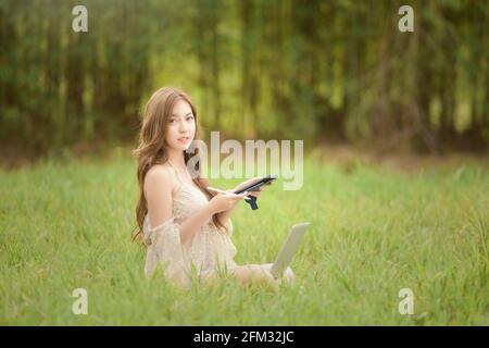 Bella donna seduta in un prato che lavora in estate, Thailandia Foto Stock