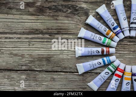 Tubi di vernice, pennelli per pittura e tavolozza coltelli sul vecchio sfondo di legno. Foto Stock