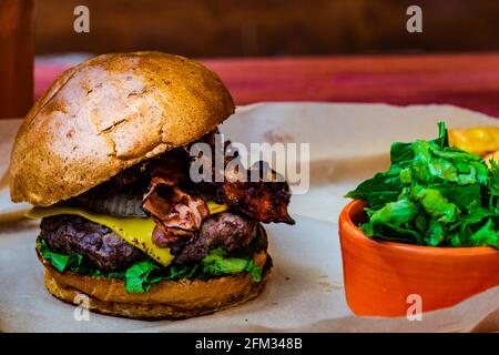 Hamburger del Texas con pancetta, formaggio, patatine fritte e insalata Foto Stock