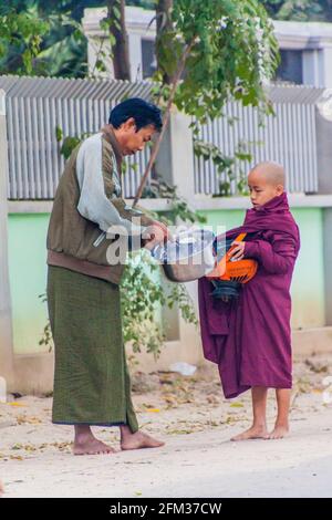 BAGAN, MYANMAR - 8 DICEMBRE 2016: Giovane monaco buddista con una ciotola che raccoglie le sue elemosine quotidiane. Foto Stock