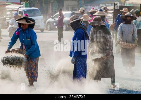 BAGO, MYANMAR - 10 DICEMBRE 2016: Lavoratori locali della strada che costruiscono una strada macadam. Foto Stock