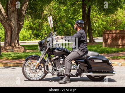 Annapolis, MD, USA 05-02-2021: Un uomo afroamericano con la barba di capra che indossa jeans, giacca, stivali e casco è al minimo sulla strada in città. Lui Foto Stock