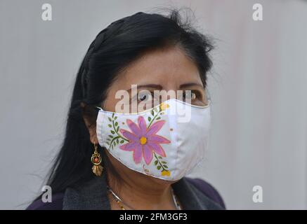 Mature bella donna messicana con gli occhi marroni bella indossa una maschera di tessuto dipinto a mano durante la pandemia coronavirus e guarda lo spettatore. Foto Stock