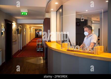 Horumersiel, Germania. 05 maggio 2021. Mario Krar, gestore di hotel e ristoranti, si trova alla reception dell'hotel. Dal 10 maggio 2021, i pernottamenti turistici in bassa Sassonia fuori dai punti caldi di Corona saranno nuovamente possibili, per il momento solo per i propri residenti. Potranno poi effettuare nuovamente il check-in in hotel, appartamenti e campeggi, insieme a test rapidi negativi o prove di vaccinazione. Credit: Sina Schuldt/dpa/Alamy Live News Foto Stock