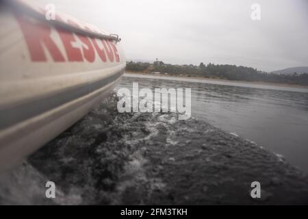 Appendere fuori il lato di una barca di salvataggio gonfiabile nella pioggia, il lago Manapouri, l'isola del sud, Nuova Zealanda Foto Stock