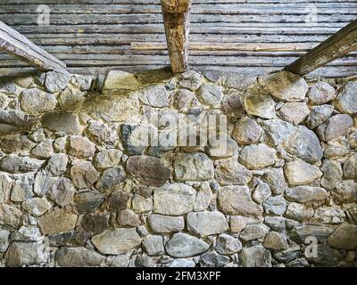 vista interna di vecchio fienile abbandonato con pareti in pietra e. travi in legno sotto il tetto Foto Stock