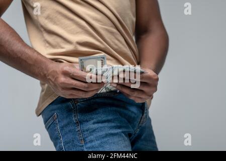 Mani di Mans che tirano fuori le banconote dalla sua tasca Foto Stock