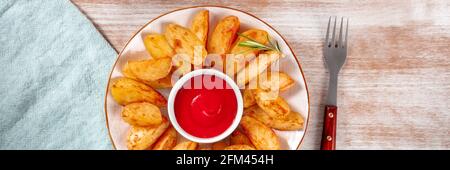 Panorama delle zeppe di patate al forno con forchetta e tovagliolo su sfondo rustico, con salsa di pomodoro biologica Foto Stock