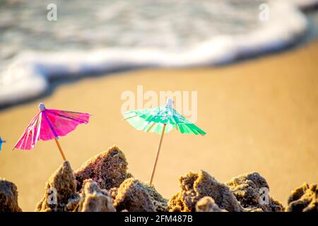 Piccoli ombrelloni da spiaggia in carta per cocktail stand in sabbia Foto Stock