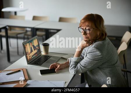 Ufficiale di affari che si proppa la testa mentre guarda al lato Foto Stock