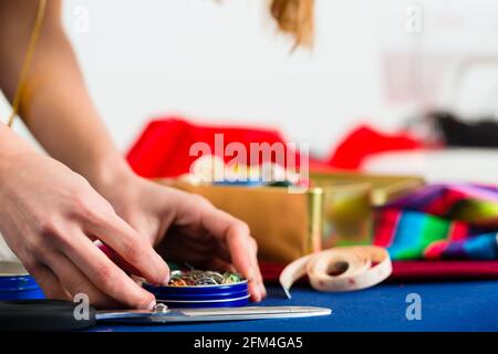 Freelance - adattare o designer che lavora con diversi utensili, come cotone bobine, spole, e tessuti colorati Foto Stock