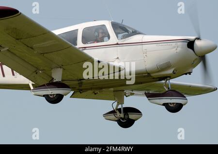 Piper PA-28 aereo leggero Cherokee in avvicinamento a terra presso l'aeroporto di Earls Colne. Pilota e copilota in cabina di pilotaggio. Volo privato PPL Foto Stock