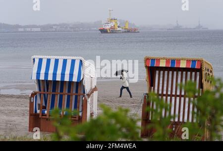 06 maggio 2021, Schleswig-Holstein, Eckernförde: Una donna cammina lungo una spiaggia sotto la pioggia. Foto: Marcus Brandt/dpa Foto Stock