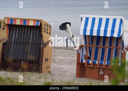 06 maggio 2021, Schleswig-Holstein, Eckernförde: Una donna cammina lungo una spiaggia sotto la pioggia. Foto: Marcus Brandt/dpa Foto Stock