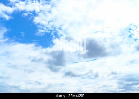 Cielo blu con le nuvole bianche e due piccole nuvole grigie al centro. Sfondo naturale del cielo. Foto Stock