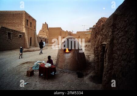 Forno per il pane su una strada che conduce alla moschea di Sankore in serata. Un ragazzo vende il pane appena sfornato ai passanti. 19.11.2003 - Christoph Keller Foto Stock