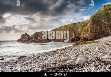 Spiaggia di ghiaia circondata da scogliere rocciose e cataste di mare in una baia vicino a Bloody Foreland, County Donegal, Irlanda Foto Stock