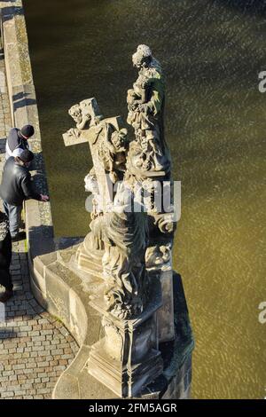 I turisti si affacciano sul Ponte Carlo sul fiume Moldava, Praga, Repubblica Ceca, sotto una statua con Madonna e Croce Foto Stock