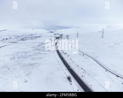 Dalwhinnie, Scozia, Regno Unito. 6 maggio 2021. Vista aerea del paesaggio innevato nel Passo di Drumochter ad alta quota a Dalwhinnie nelle Highlands scozzesi. PIC; l'autostrada A9 si snoda verso nord attraverso un Passo Drumochter coperto di neve. Iain Masterton/Alamy Live News Foto Stock