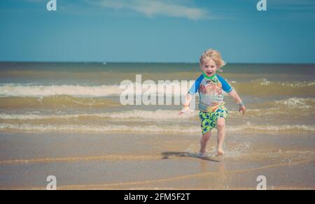 Giovane ragazzo biondo che gioca sulla spiaggia Foto Stock