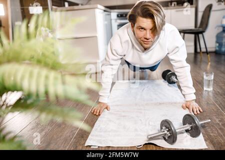 Il maschio concentrato sta lavorando fuori a casa nella mattina, facendo la posa della tavola. L'uomo caucasico atletico sta addestrando, esercitandosi per mantenere la buona figura Foto Stock