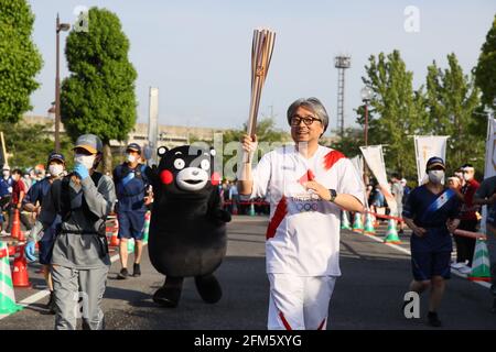 (210506) -- TOKYO, 6 maggio 2021 (Xinhua) -- Koyama kundo (davanti), il progettista della mascotte Kumamon (dietro) corre con la torcia durante il relè della torcia olimpica di Tokyo nella prefettura di Kumamoto, Giappone, 6 maggio 2021. (Tokyo 2020/Handout via Xinhua) Foto Stock
