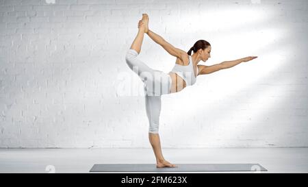 Donna flessibile in piedi nella posa danzante shiva yoga Foto Stock