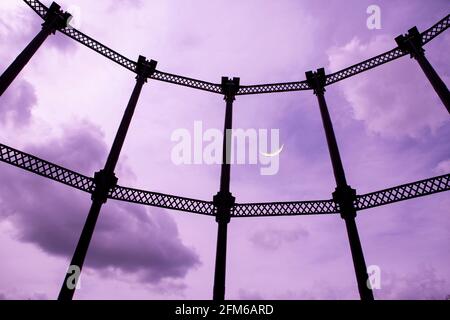 Cielo nuvoloso viola con luna e telaio portavalvole a gas Foto Stock