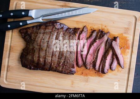 Bistecca di fiancate alla griglia marinata di Bourbon: Bistecca di fiancate medio-rare a fette su una tavola di bambù Foto Stock