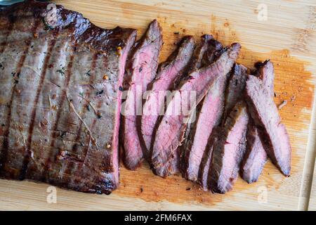 Bistecca di fiancate alla griglia marinata di Bourbon: Bistecca di fiancate medio-rare a fette su una tavola di bambù Foto Stock