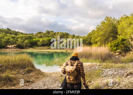 Il viaggiatore è dotato di zaino che torna indietro verso il bellissimo lago Foto Stock