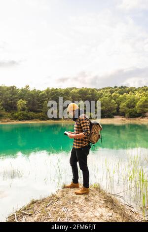 Il viaggiatore che legge la guida mentre esplora il bellissimo lago facendo turismo Foto Stock