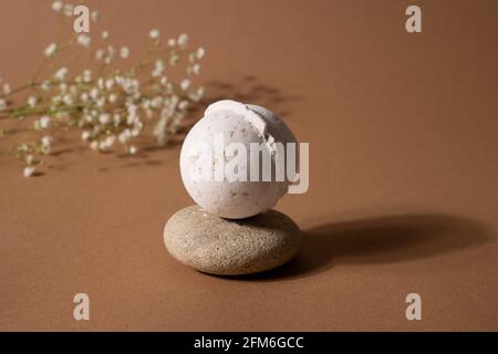 Bomba bagno aroma vaniglia in composizione termale con fiori secchi e pietra su sfondo marrone. Arrangiamento aromaterapico, Zen still life, salute e cura del corpo, trend concept con ombra Foto Stock