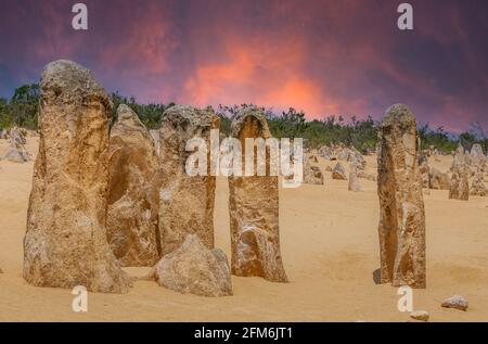 Tramonto sopra i pinnacoli nel Parco Nazionale di Nambung in Occidente Australia con ornamenti giallo dorato in primo piano contro il rosso caldo e orang Foto Stock