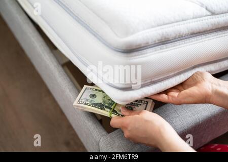 Soldi di risparmio delle fatture del dollaro sotto il materasso della base Foto Stock