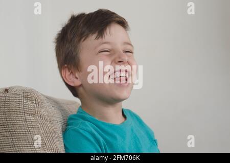 Ritratto di ragazzo sorridente utilizzando una t-shirt blu e. guardando di lato Foto Stock