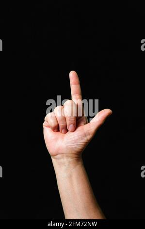 Mano che fa e mostra lettera L International segno lingua scuro sfondo Foto Stock