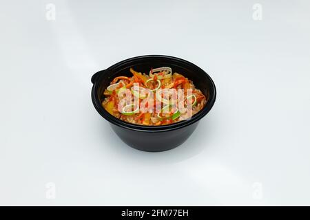 Maccheroni italiani caldi in un piatto usa e getta per la consegna di cibo, pasta fast food ad alta caloria su fondo bianco Foto Stock