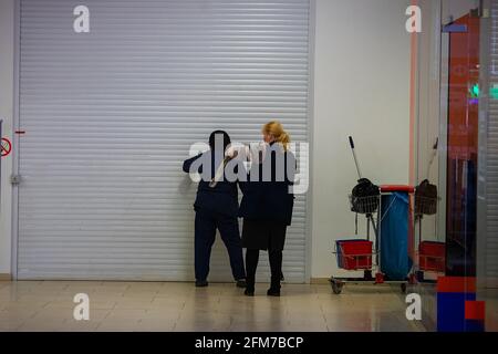 due detergenti lavano e disinfettano la parete di un negozio in quarantena in un centro commerciale, curando la pulizia durante una pandemia di coronavirus Foto Stock