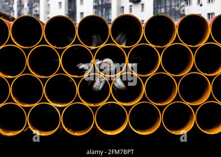 Pila di tubi rotondi termoplastici in polietilene in materiale industriale in un cantiere. Foto Stock