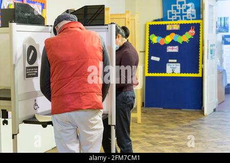 Uomo in gilet rosso al seggio per le elezioni del Regno Unito 2021, il 6 maggio. "Super Thursday", un mostro elettorale, Inghilterra Foto Stock