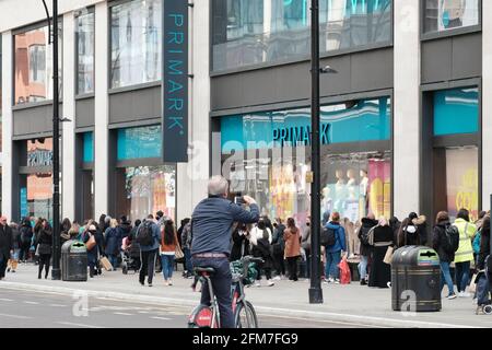 Un uomo in bicicletta scatta una foto di Coda al di fuori di un archivio Primark il primo giorno non essenziale i negozi hanno riaperto come parte del blocco di alleggerimento Foto Stock