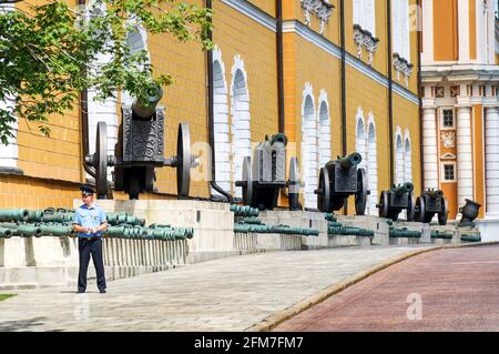 MOSCA, RUSSIA - 06 14 2016: Un poliziotto di fronte alla vecchia esposizione di artiglieria nel Cremlino di Mosca. C'è una collezione museale di artiglieria di XVI Foto Stock
