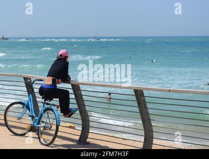 Una donna seduta sulla sua bicicletta e godendo la vista del Mediterraneo dal lungomare di Tel-Aviv, Israele. Foto Stock