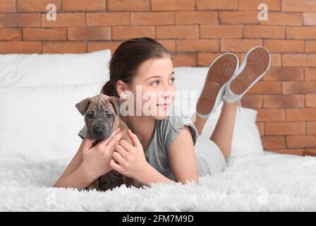 Ragazza carina con cucciolo sdraiato sul letto a casa Foto Stock