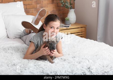 Ragazza carina con cucciolo sdraiato sul letto a casa Foto Stock