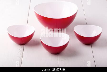 Una ciotola di insalata rossa vuota e tre tazze su a. tavolo di legno bianco Foto Stock